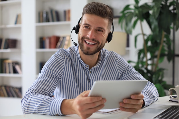 Homem confiante usando fone de ouvido, falando e assistindo o treinamento do webinar de negócios, ouvindo a palestra.