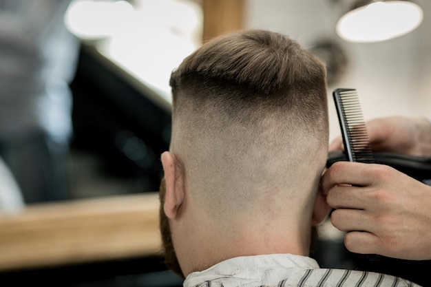 Homem confiante visitando o cabeleireiro na barbearia. Vista traseira