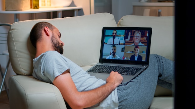 Homem confortável de pijama adormecendo enquanto conversa com os colegas