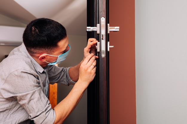 Homem consertando a maçaneta da porta. close das mãos do trabalhador instalando novo armário de porta