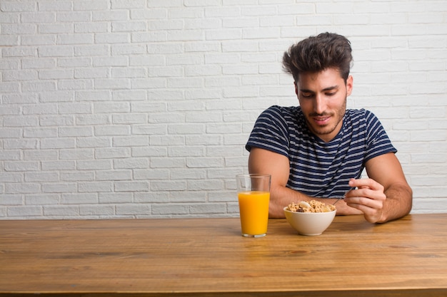 Homem considerável e natural novo que senta-se em uma tabela que ri e que tem o divertimento, sendo relaxado e alegre