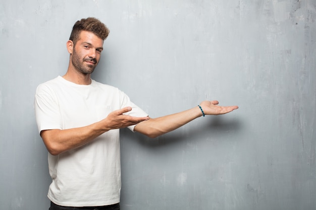 Homem considerável novo que sorri com um olhar orgulhoso, satisfeito e feliz, gesto de acolhimento