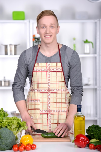 Homem considerável que cozinha em casa a preparação da salada na cozinha.