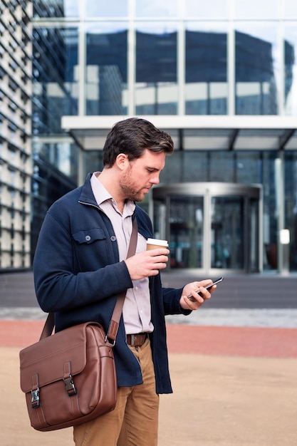 Homem consultando telefone na entrada do escritório