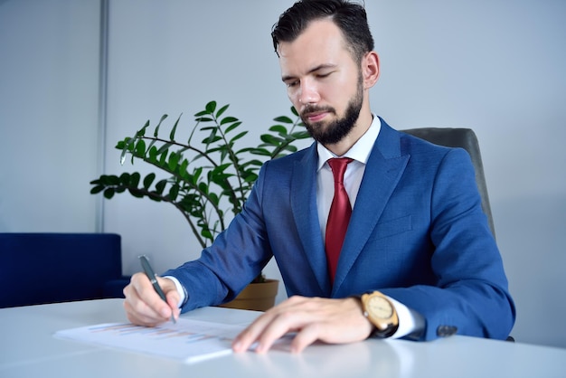 Homem contador sentado no escritório e analisando o relatório de negócios