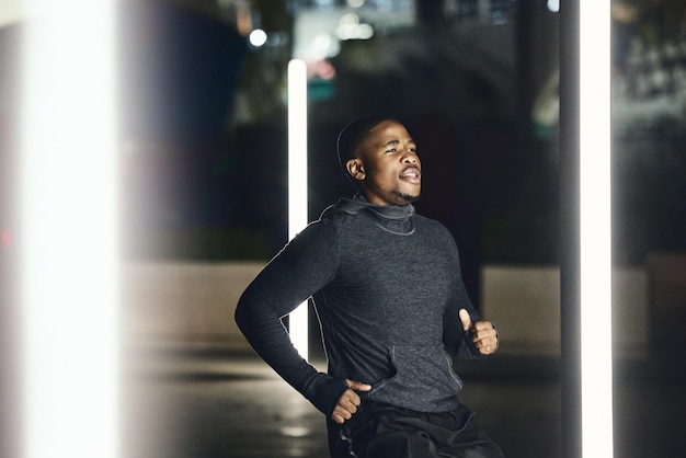 Homem corredor africano noite e cidade para treinar exercícios de velocidade ou bem-estar na rua escura com foco Homem negro correndo treino noturno e metrô urbano para equilíbrio físico ou corrida rápida na Cidade do Cabo