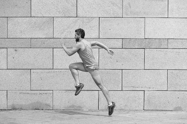 Homem corredor masculino correndo para o sucesso esportivo de sucesso Esforçando-se pela vitória homem ativo em roupas esportivas pulando enquanto se exercita ao ar livre cara correndo na rua Salto para a frente