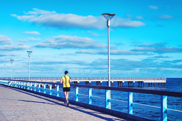 Homem correndo ao longo da ponte do mar no mar Báltico no resort Palanga, Lituânia