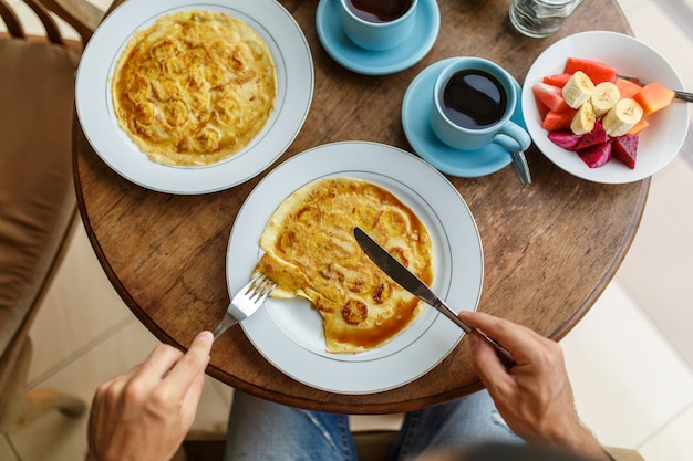 Homem corta café da manhã panquecas de banana