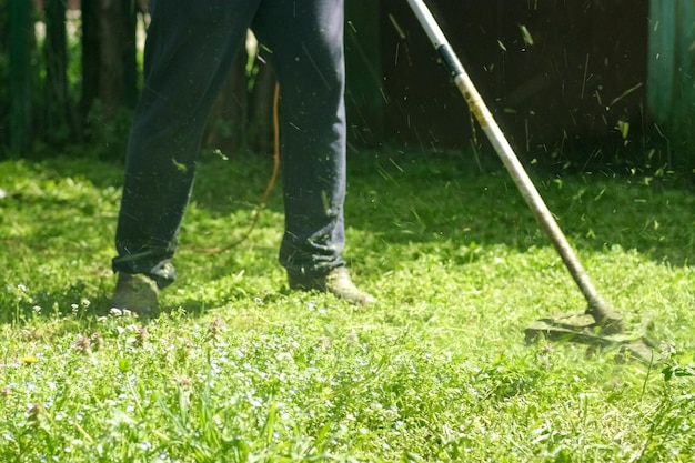 Homem corta grama com cortador de grama elétrico manual no jardim conceito de trabalho de jardim