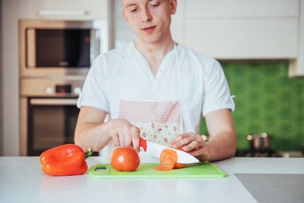 Homem corta legumes juntos na cozinha