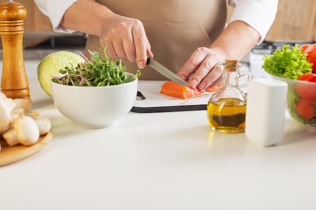 Homem corta pimenta na mesa na cozinha