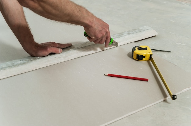 Foto homem corta um pedaço de drywall