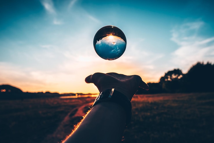 Foto homem cortado pegando uma bola de cristal contra o céu durante o pôr do sol