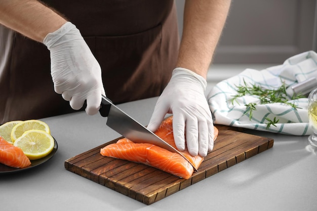 Homem cortando filé de salmão fresco na cozinha