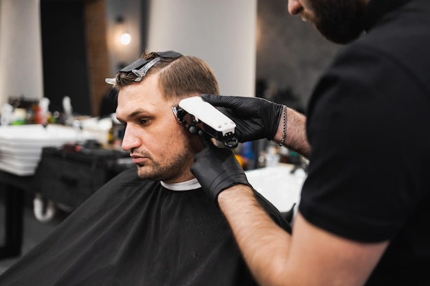 Homem cortando o cabelo enquanto está sentado em uma cadeira de barbearia