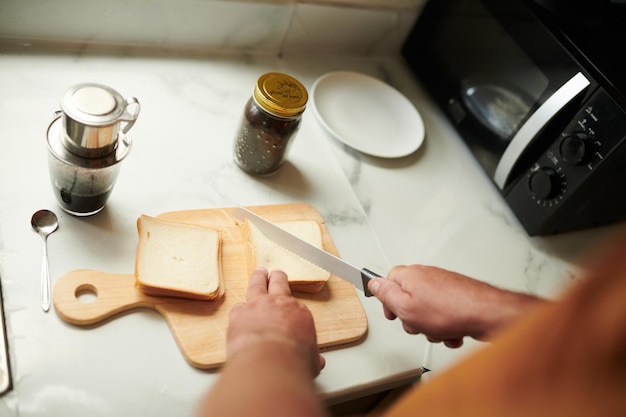 Homem cortando pão em triângulos