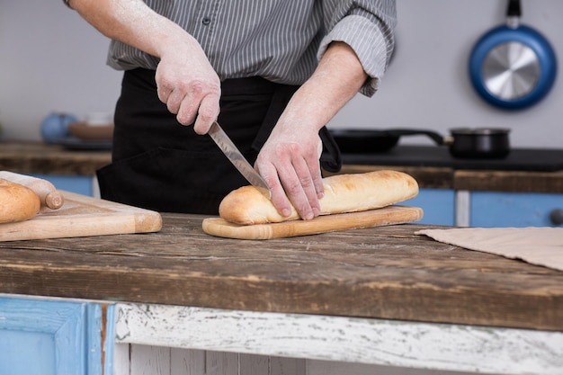 Homem cortando pão na cozinha