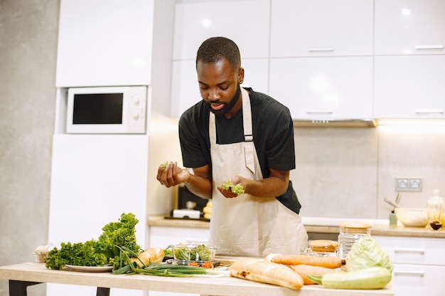 Homem cozinhando. homem afro-americano em uma cozinha. homem de camiseta preta.