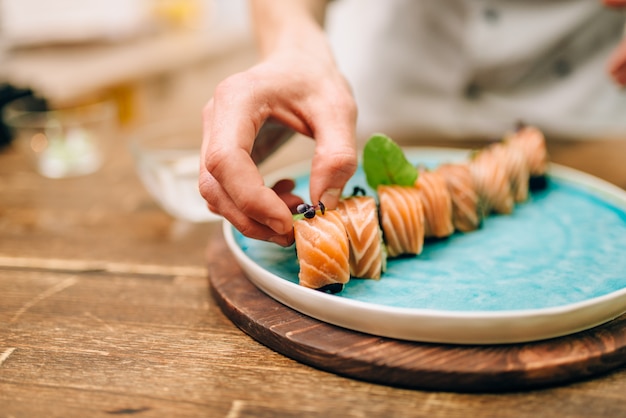 Homem cozinhando rolinhos de sushi com salmão