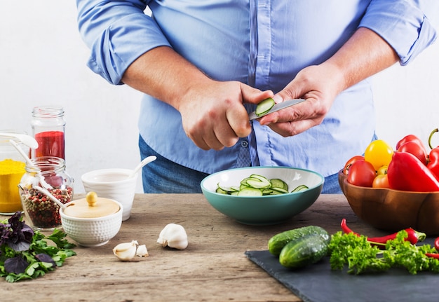 Homem cozinhando uma salada vegetariana