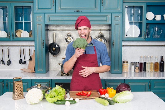 Homem cozinhar receita vegetariana com legumes frescos. Conceito de dieta vegetariana. Receita culinária. Chef cozinhando receita vegetariana. Vitaminas ricas na culinária vegetariana. Chef de homem usa avental cozinhando na cozinha.