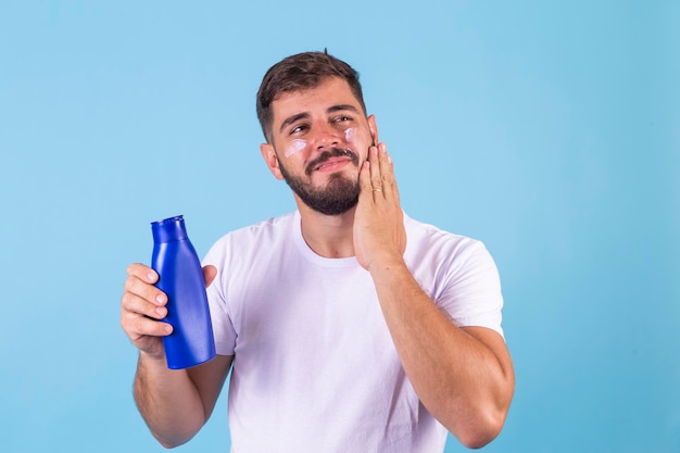 Homem cuidadoso aplicando creme corporal e facial para hidratar a pele