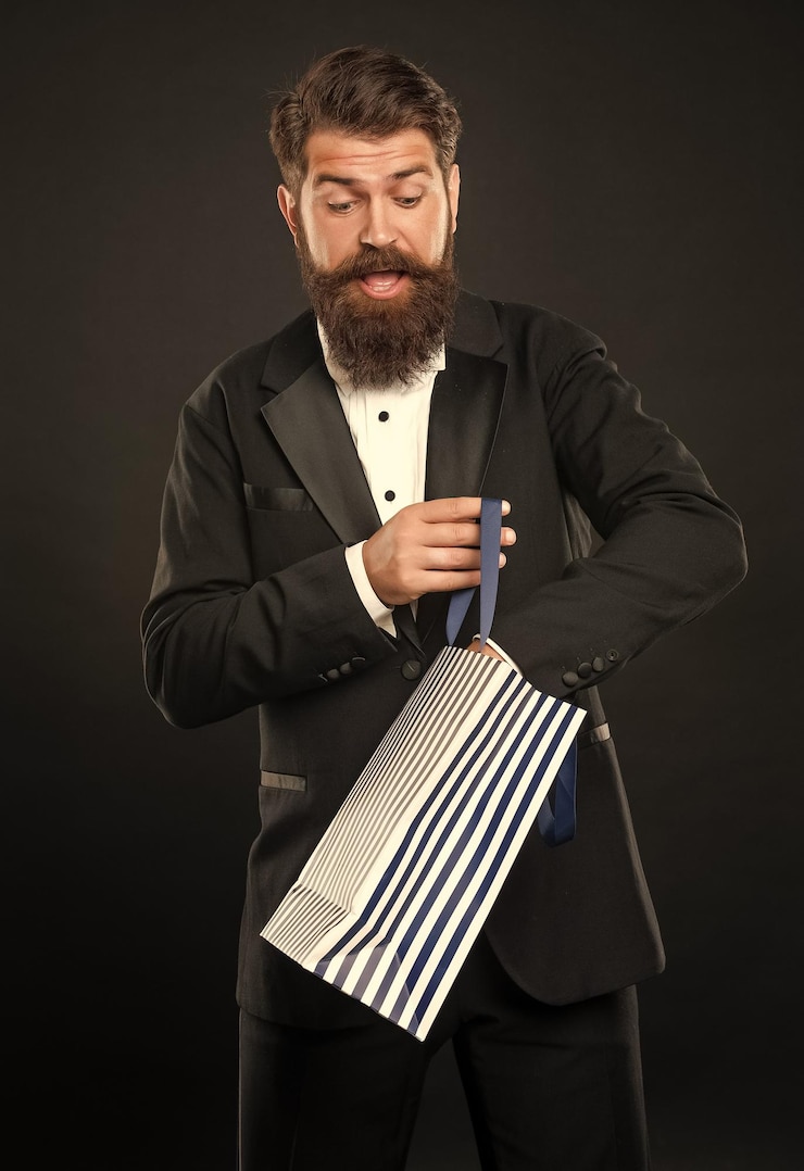 Foto homem curioso espantado com gravata de smoking roupa formal em fundo preto com saco de compras para o dia dos homens