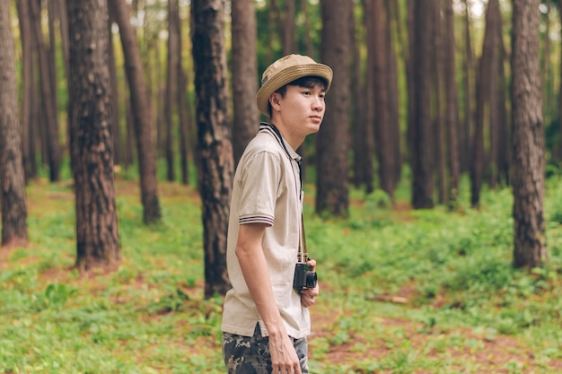 Homem da ásia usa camisa, chapéu e calças de camuflagem estão andando e tirando fotos na floresta