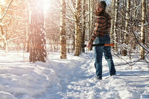 Homem da floresta de inverno de vidoeiro com machado