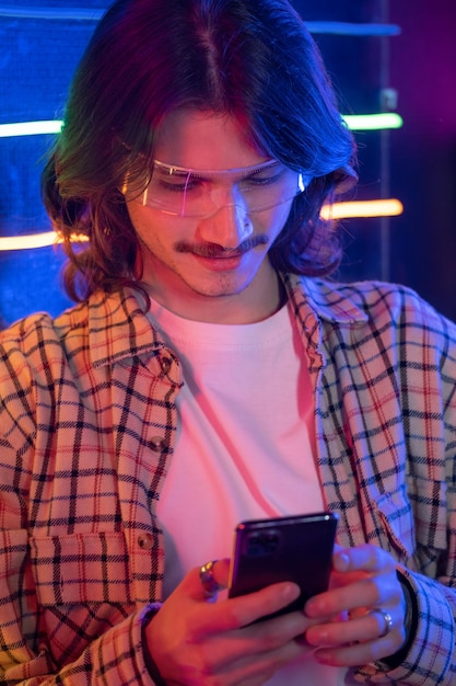 Homem da noite usando smartphone na caixa de telefone antiga à noite com luz neon