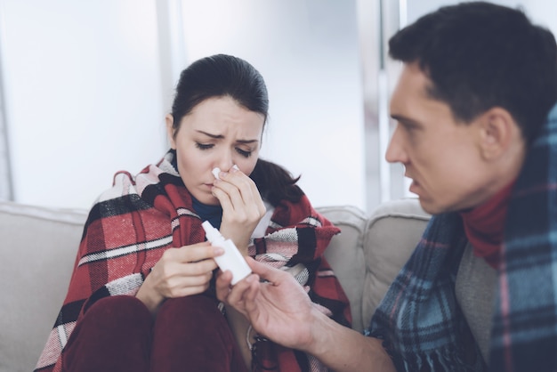 homem dá spray nasal de mulher em casa.