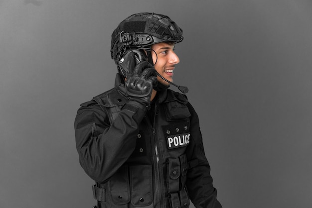 Homem da SWAT caucasiano isolado em um fundo cinza, conversando com alguém ao telefone celular
