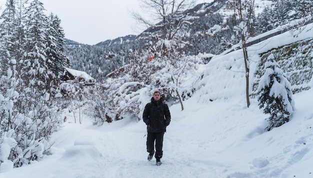 Homem dá um passeio na neve com as montanhas ao fundo