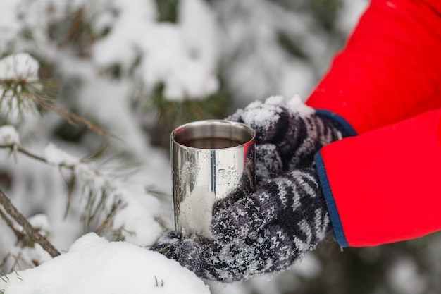 homem dá uma xícara de chá ou café quente, aproveitando a manhã de inverno acolhedor e nevado ao ar livre