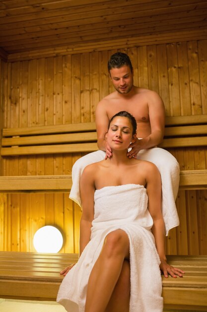 Homem dando a sua namorada uma massagem no pescoço na sauna