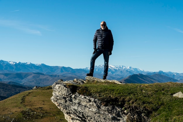 Homem de 60 anos posando após uma caminhada na montanha no norte da Espanha com uma bela paisagem natural
