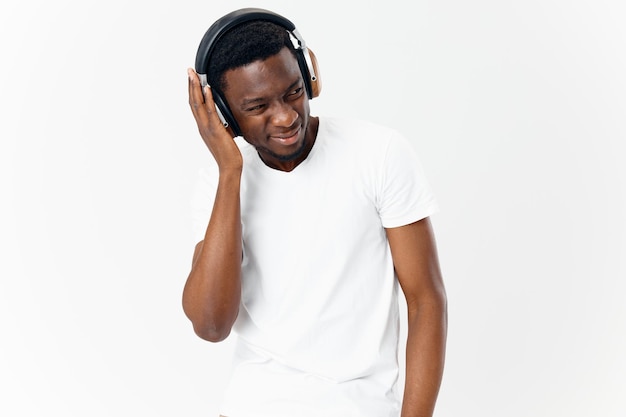 Homem de aparência africana com camiseta branca e fones de ouvido, ouvindo estúdio de tecnologia musical