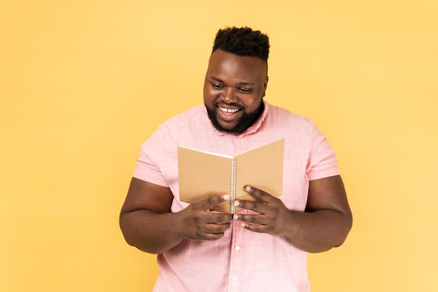 Homem de aparência agradável encantado segurando livro lendo romance interessado expressando emoções positivas