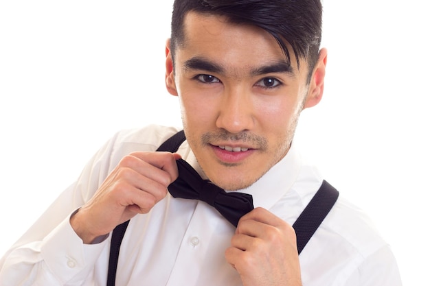 Homem de aparência inteligente na camisa branca com gravata preta e suspensórios pretos sobre fundo branco no estúdio