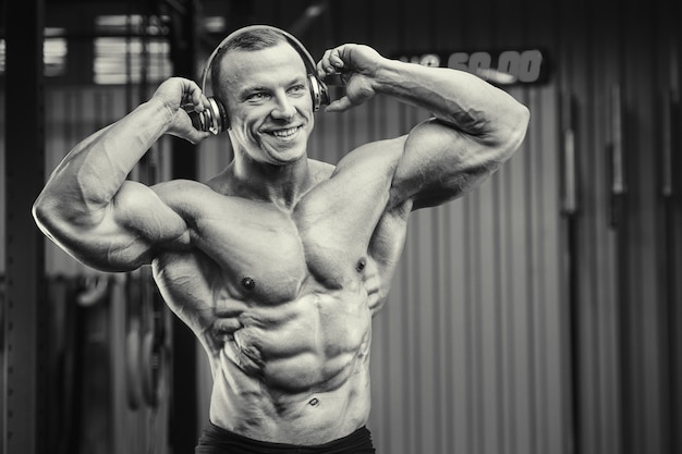 Homem de aptidão com fones de ouvido no treino no ginásio. Conceito de musculação