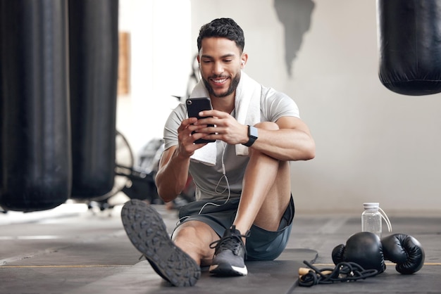 Homem de aptidão com smartphone e fones de ouvido na academia feliz por treinamento ou bem-estar de saúde Meditação ou exercício de compromisso ou treino e atleta masculino ouve música ou podcast para motivação