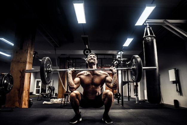 Homem de aptidão muscular fazendo levantamento terra um barbell na cabeça no moderno centro de fitness