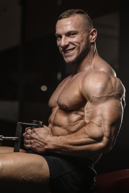 Foto homem de aptidão muscular fisiculturista fazendo exercícios de braços no ginásio