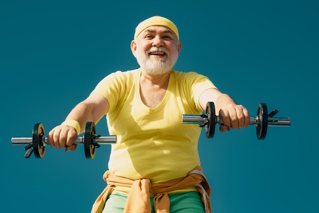 Foto homem de aptidão sênior treinando com halteres isolados em fundo azul levantando halteres retrato de