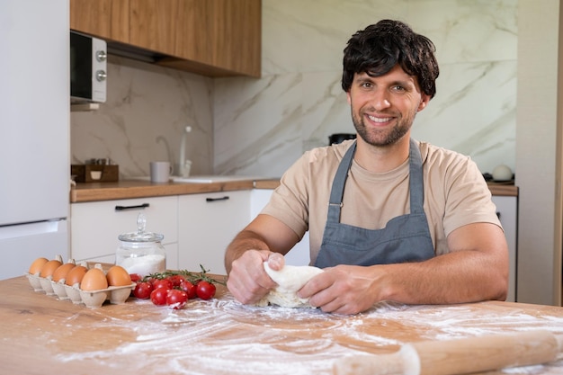 Homem de avental que amassa massa e assa um bolo delicioso para uma festa usa vários ingredientes O conceito de trabalho doméstico e culinária