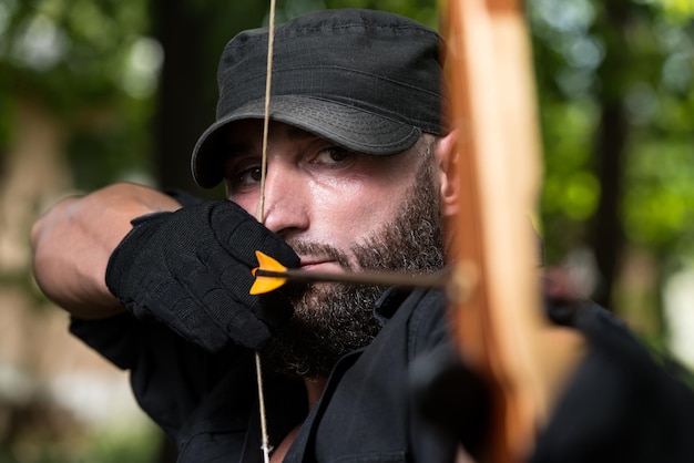 Homem de barba com um arco e flechas na floresta