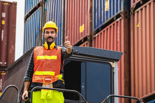 Homem de barba de engenheiro em pé com ware um capacete amarelo para controlar o carregamento e verificar a qualidade dos contêineres do navio de carga de carga para importação e exportação no estaleiro ou porto