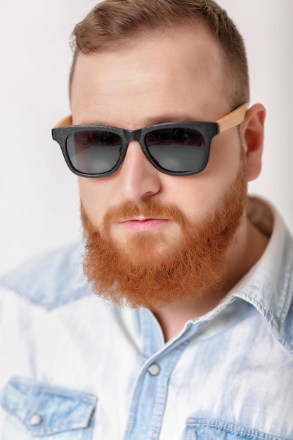 Homem de barba em óculos de sol e camisa jeans