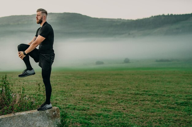 Homem de barba jovem e bonito estendendo-se na natureza